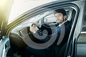 Happy owner. Handsome bearded man sitting relaxed in his newly bought car