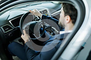 Happy owner. Handsome bearded man sitting relaxed in his newly bought car