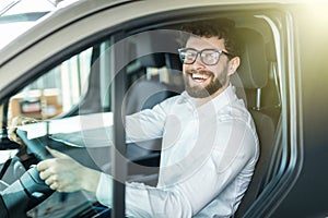 Happy owner. Handsome bearded mature man sitting relaxed in his newly bought car looking out the window smiling joyfully