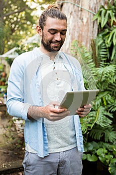 Happy owner using digital tablet at garden