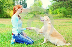 Happy owner woman training Golden Retriever dog on grass in park