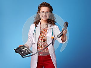 Happy paediatrician doctor with phone on blue