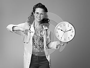 Happy paediatrician doctor pointing at clock on