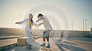 Happy pair riding skate boards sunny stadium. Carefree couple enjoying summer