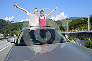 Happy pair in sunroof of car on highway near photo