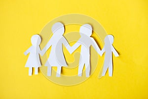 Happy paper cut family holding hands on yellow background