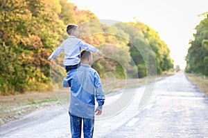 A Happy parent with a child in the park hands on nature travel go along the road