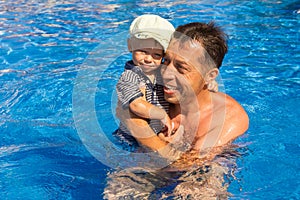 Happy parent with child playing in a swimming pool on nature by the sea