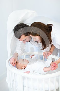 Happy parent looking at their baby son in round crib