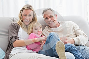 Happy parent tickling their cute daughter on the couch