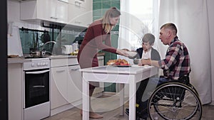 Happy parenting, disabled father has fun with loving wife and a happy son while cooking for his family