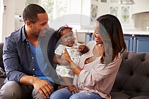 Happy parents with baby girl standing on mumï¿½s knee