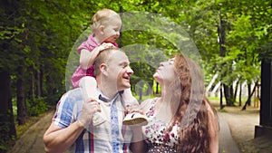 Happy parents with baby girl walking in a park