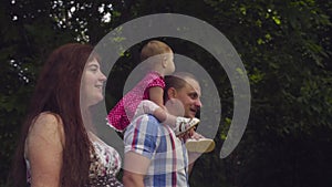 Happy parents with baby girl walking in a park