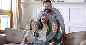 Happy parents bonding with children on couch looking at camera