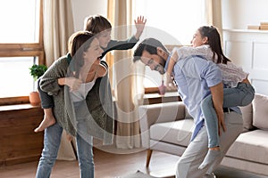 Happy parents carrying children on backs, having fun at home