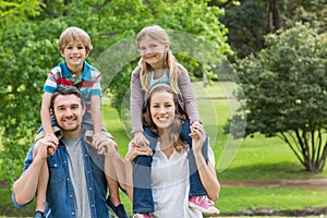 Happy parents carrying kids on shoulders at park