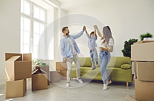 Happy parents and child playing and having fun in the living room in their new house