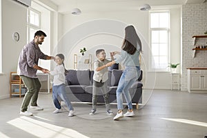 Happy parents and children dancing and having fun in their new house or apartment