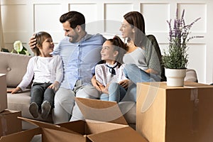 Happy parents with children relaxing on sofa on moving day