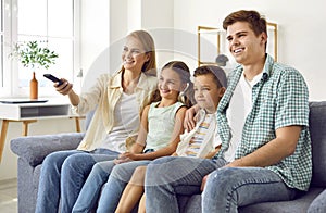 Happy parents and children sitting on the couch and watching television together