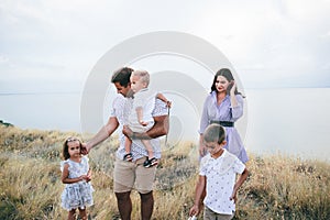 Happy parents and children speaking outdoors in a wheat field and river view.
