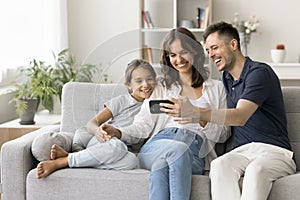 Happy parents and cute daughter kid watching content on smartphone