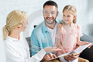 happy parents with cute little daughter reading book together