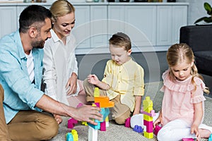 happy parents with cute little kids playing with colorful blocks