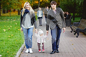 Happy parents with daughter going on path in park