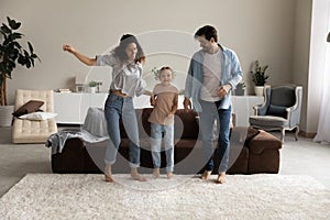 Happy parents with daughter jumping in modern living room together