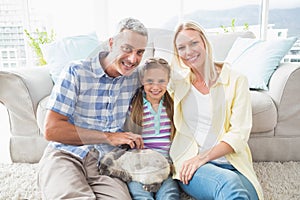 Happy parents and daughter with rabbit in living room