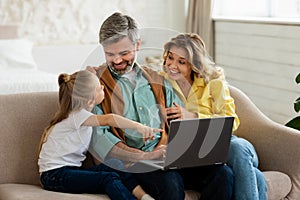 Happy Parents And Daughter Using Laptop Together At Home