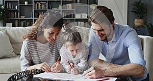 Happy parents draw pictures with little daughter.