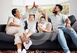 Happy parents and excited children celebrate on the sofa while watching tv. Fun family time, relaxing at home and