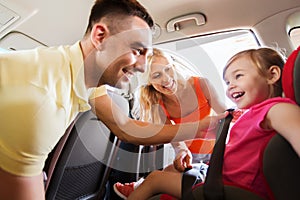 Happy parents fastening child with car seat belt