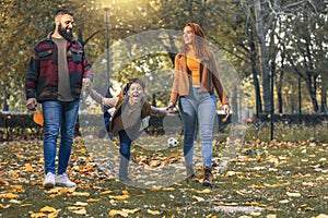 Happy parents having fun with their boy while running in the park during autumn day