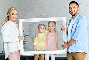 happy parents holding frame and cute little children