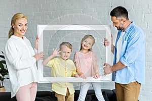 happy parents holding frame and cute little kids smiling