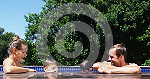 Happy parents interacting with kids in swimming pool