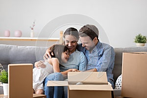 Happy parents with kid embracing on sofa enjoy moving day