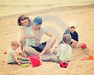 Happy parents and kids toying with sand