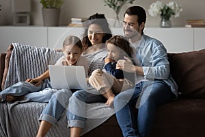 Happy parents with kids using laptop at home together