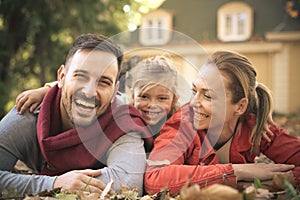 Happy parents with little girl laying on ground, poses to camera