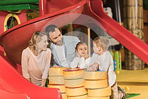 happy parents looking at adorable little kids playing together