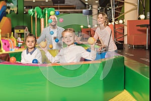 happy parents looking at cute little kids smiling at camera and playing with colorful balls