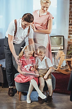 happy parents looking at cute little kids using digital tablet 1950s