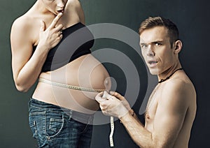 Happy parents measuring on pregnant woman's belly