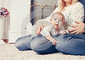 happy parents play with their baby near the fireplace in the living room