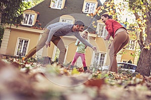 Happy parents playing with daughter. Autumn season. On the move.